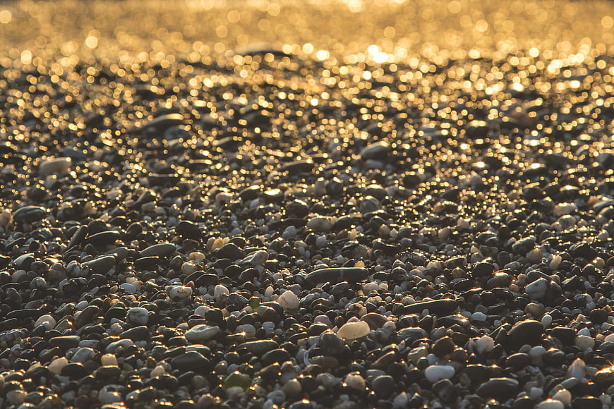 Golden sunlight reflecting on wet pebbles at the beach
