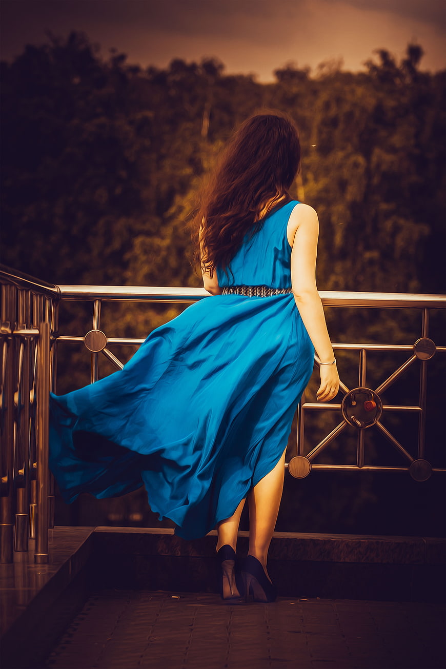 Woman in Blue Dress Sitting on Balcony at Sunset