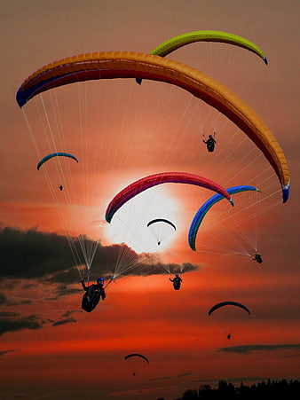 Colorful Paragliders Soaring Against a Dramatic Sunset Sky