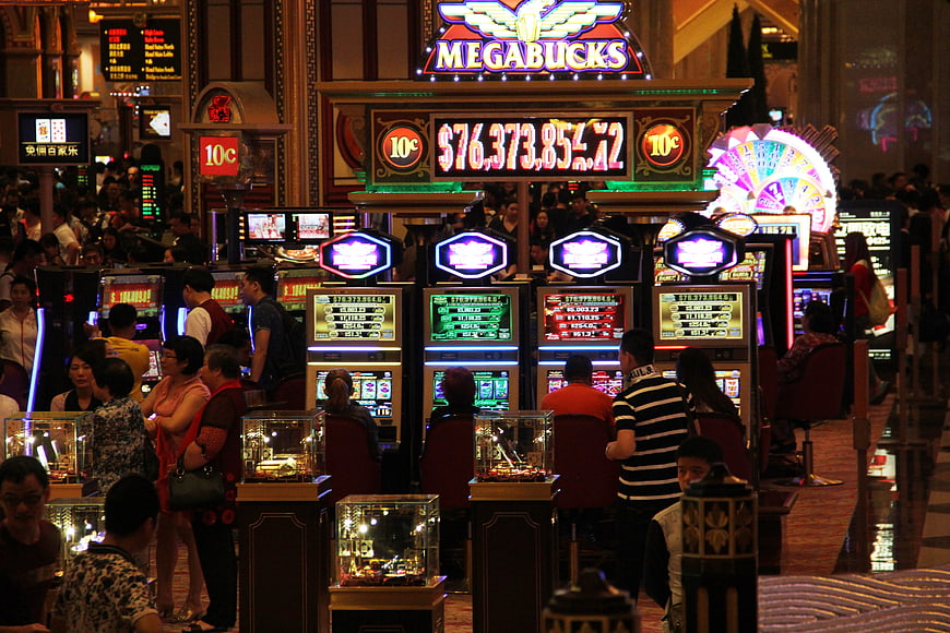Crowded Casino Floor With Slot Machines And Bright Neon Signs