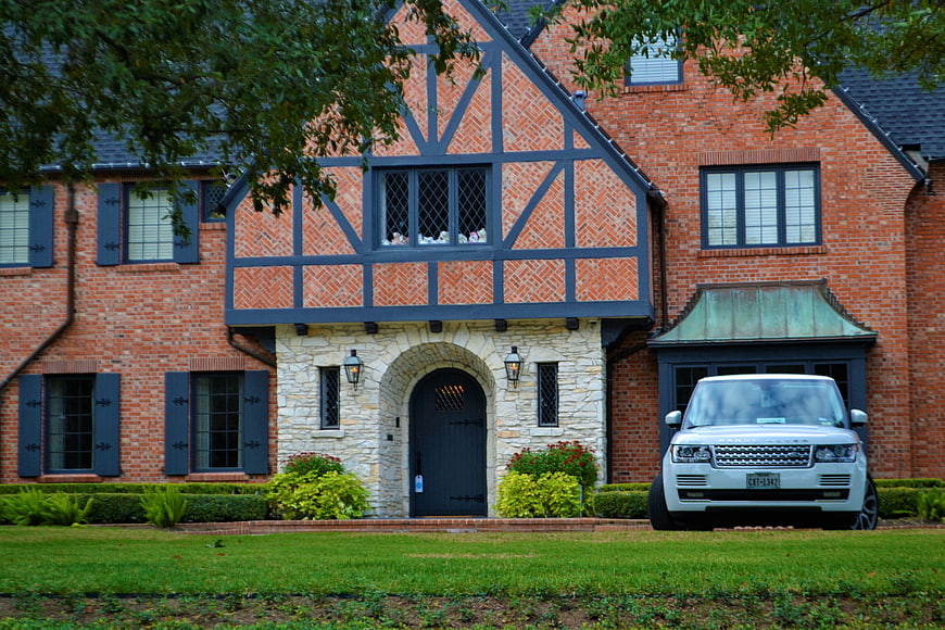 Luxury Tudor Brick Home with White SUV in Driveway