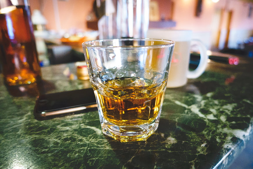 Glass of whiskey on green marble bar counter