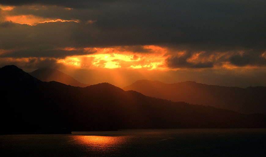 Dramatic Sunset Over Silhouetted Mountains and Ocean