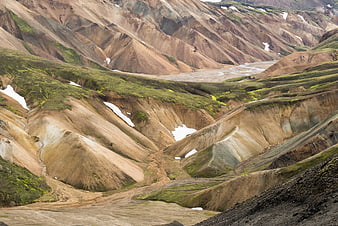 Colorful volcanic landscape with mossy hills and snow patches