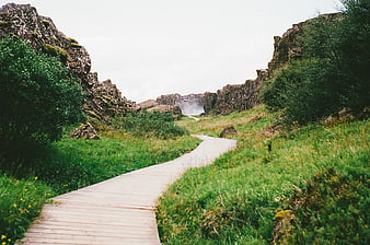 Wooden boardwalk path through rocky canyon to waterfall