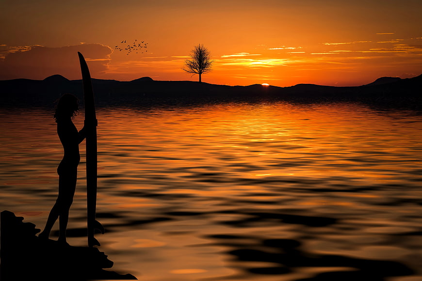 Silhouette of Woman with Surfboard at Sunset
