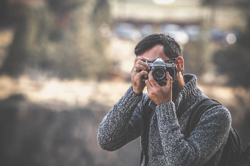 Man Taking Photo with Vintage Film Camera Outdoors