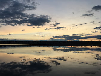 Serene Lake Sunset with Cloud Reflections and Silhouette