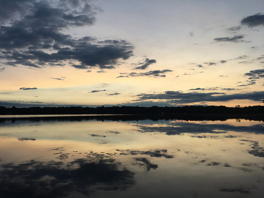 Serene Lake Sunset with Cloud Reflections and Silhouette