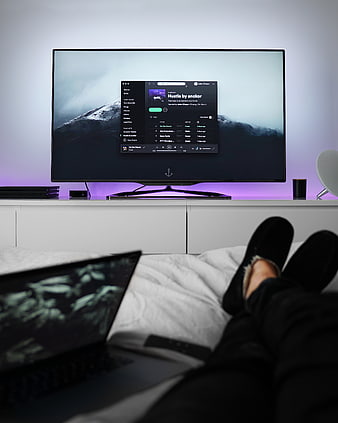 Relaxing in bed with laptop and TV streaming music