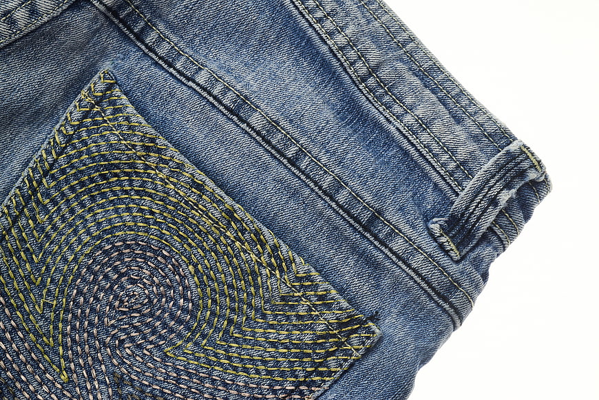 Close-up of blue denim jeans pocket with yellow stitching