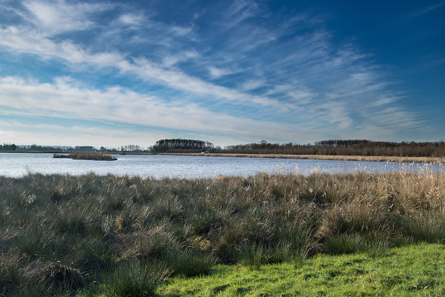 Serene Lake Landscape with Blue Sky and Wispy Clouds