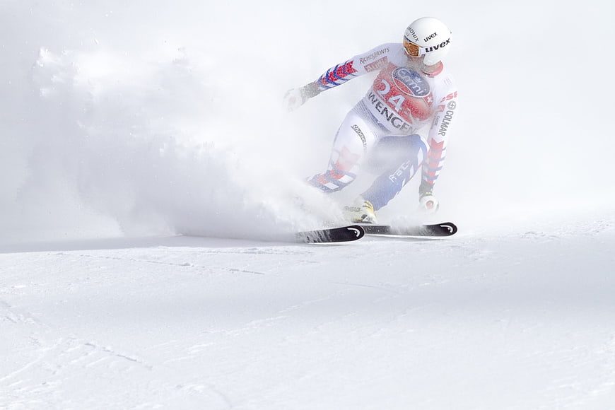 Alpine skier carving turn in powder snow race