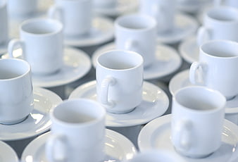 White ceramic coffee cups and saucers arranged on a table