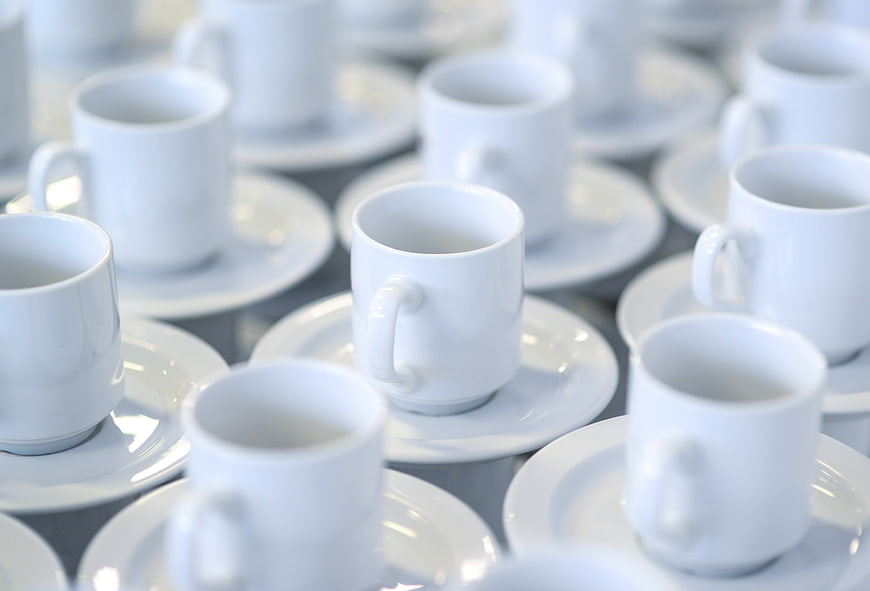 White ceramic coffee cups and saucers arranged on a table