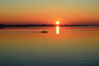 Silhouette of a Canoeist Paddling on a Calm Lake at Sunset