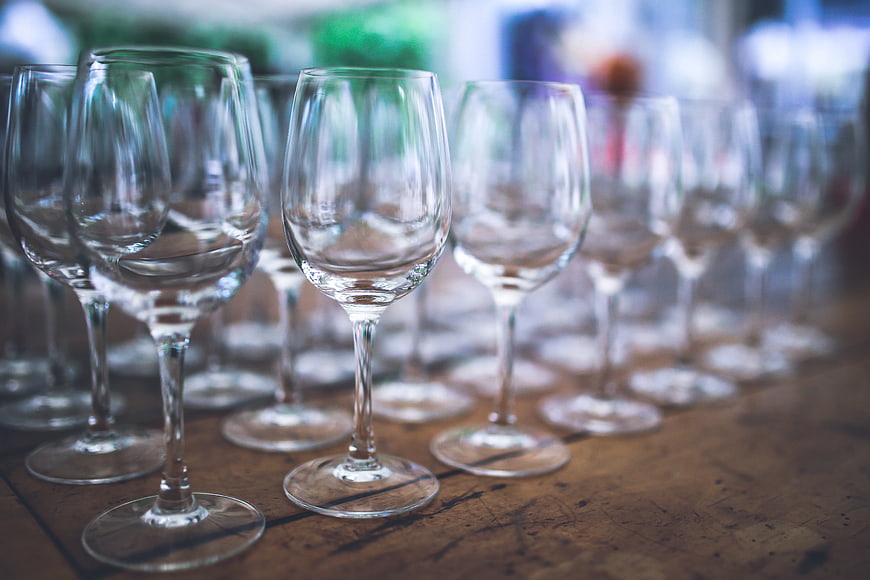 Rows of empty wine glasses on a rustic wooden table