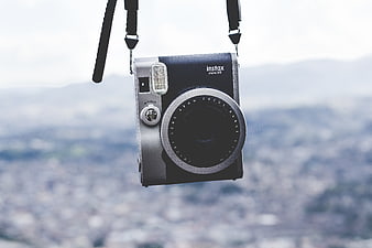 Fujifilm Instax Mini 90 Camera Hanging Against City View