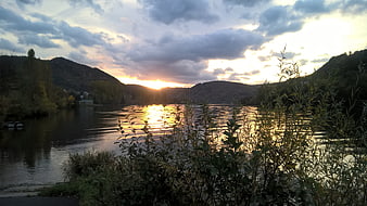 Serene River Sunset with Golden Reflections and Cloudy Sky