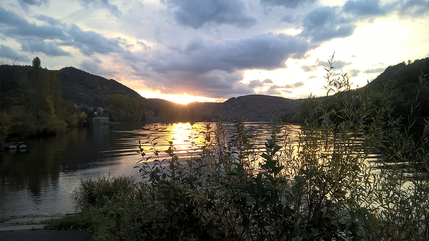 Serene River Sunset with Golden Reflections and Cloudy Sky