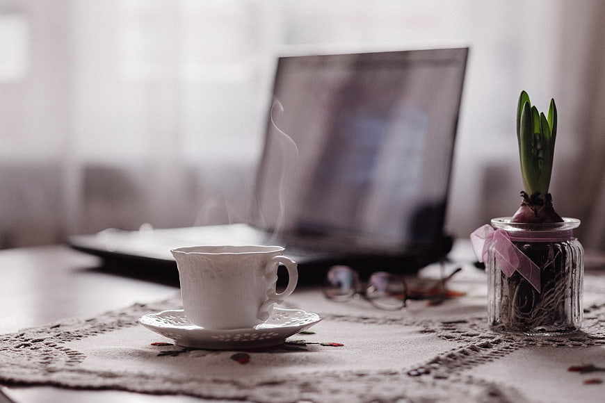 Steaming Tea Cup and Laptop on Lace Tablecloth