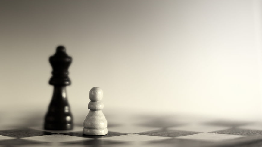 Black and white chess pieces on a board with shallow depth of field