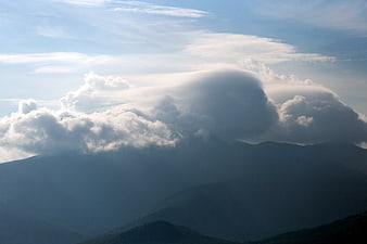 Dramatic lenticular clouds over misty mountain landscape