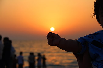 Baby Silhouette Holding Sun at Sunset on Beach