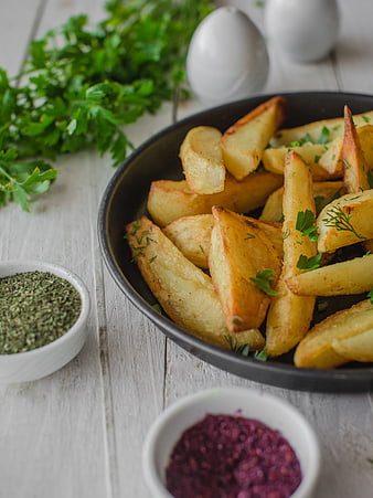 Roasted potato wedges with herbs and spices on rustic table