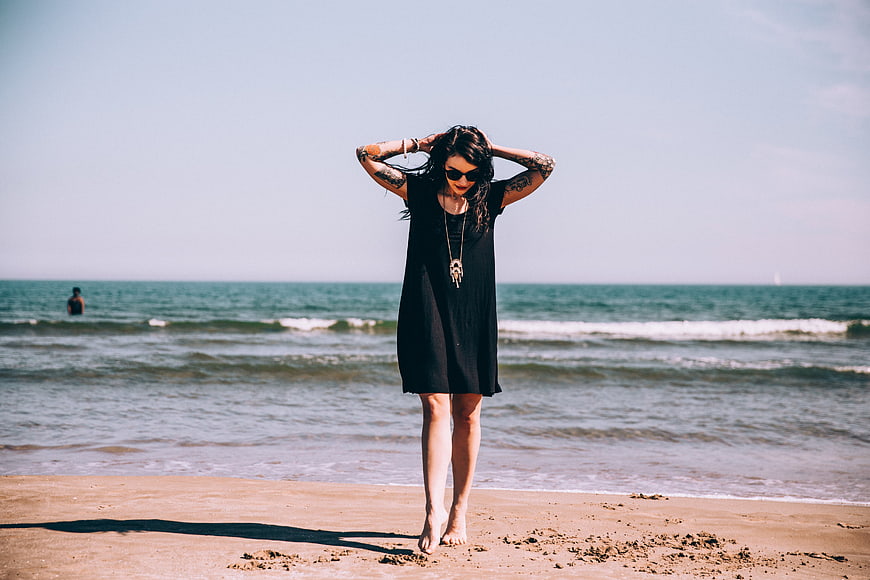 Woman with Tattoos Standing on Sandy Beach