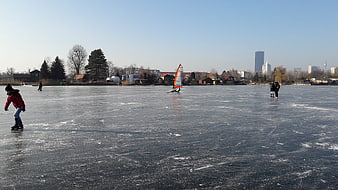 Ice Skating and Windsurfing on Frozen Lake in Winter