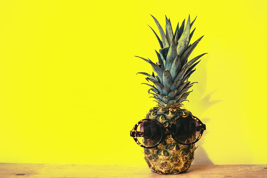 Cool pineapple wearing sunglasses on yellow background