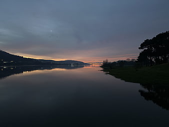 Serene Lake Sunset with Reflections and Silhouetted Trees