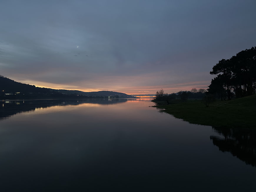 Serene Lake Sunset with Reflections and Silhouetted Trees