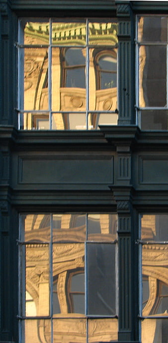 Reflection of ornate building in dark window panes