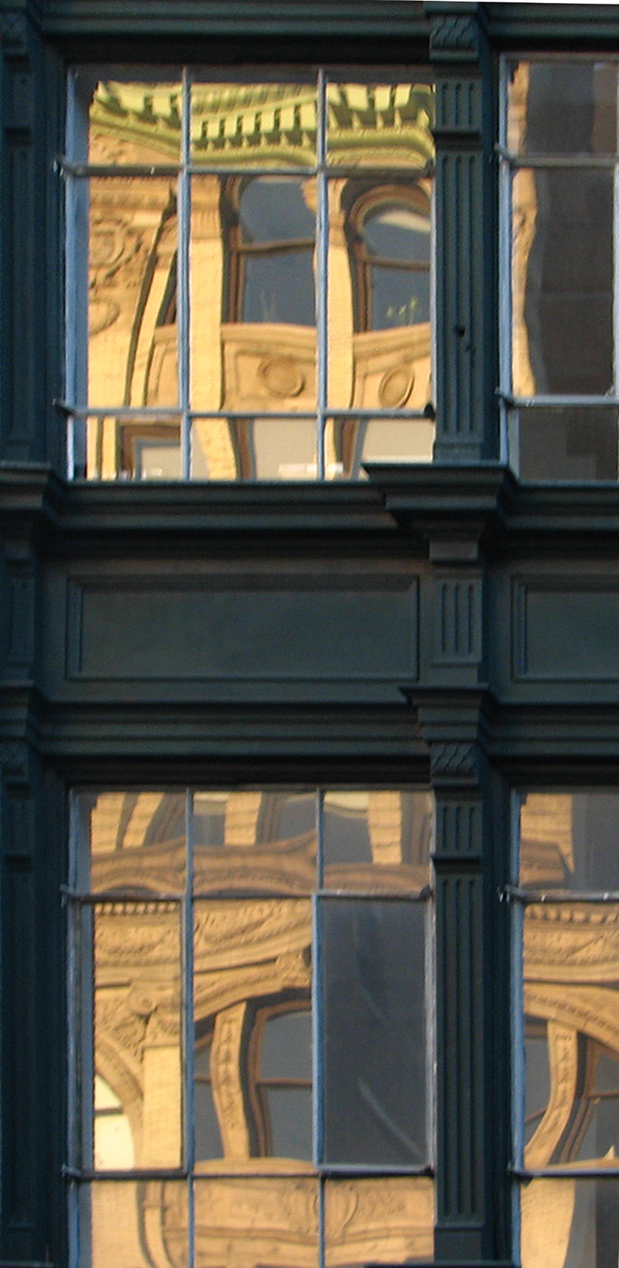 Reflection of ornate building in dark window panes