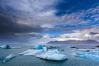 Dramatic Blue Icebergs Floating in Glacial Lagoon Under Cloudy Sky