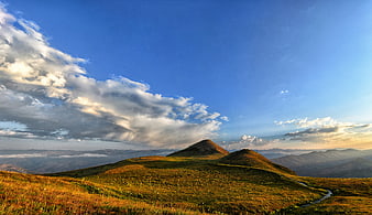 Panoramic Mountain Landscape with Golden Grass and Blue Sky