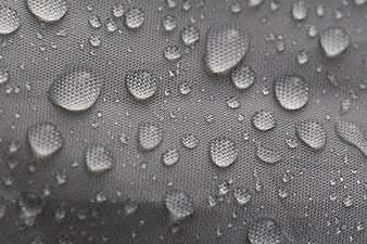 Macro shot of water droplets on gray waterproof fabric texture