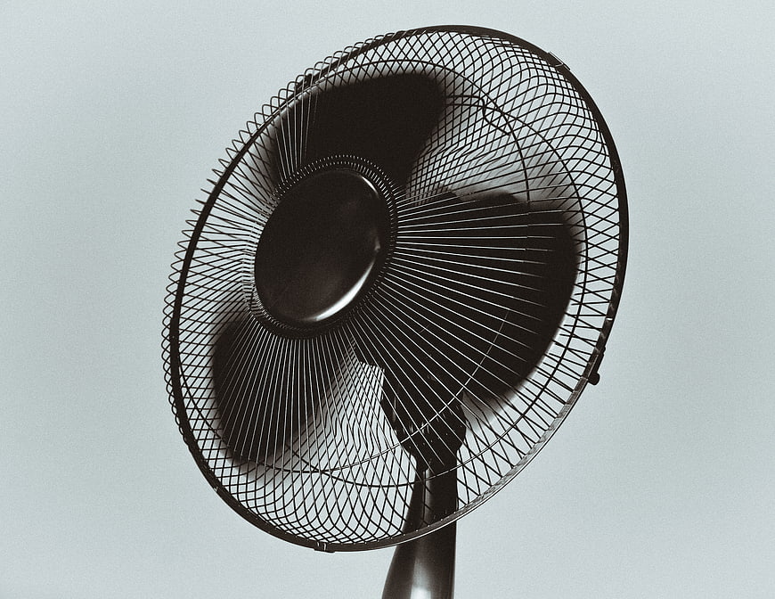 Black electric fan spinning against a gray background
