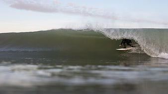 Surfer riding inside a large ocean wave barrel