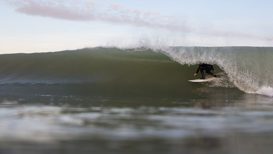 Surfer riding inside a large ocean wave barrel