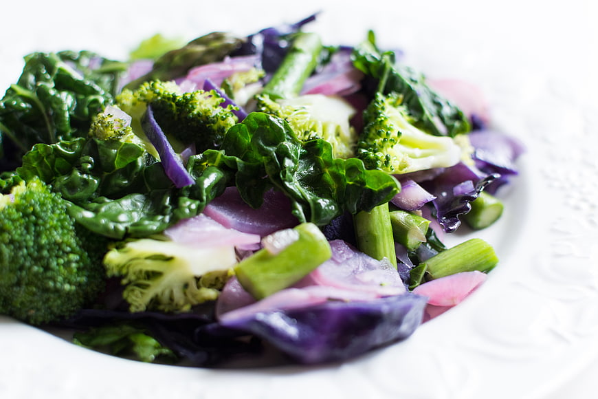 Sauteed broccoli, kale, and red cabbage on white plate
