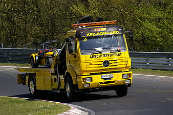 Yellow Mercedes Tow Truck Transporting Race Car on Track