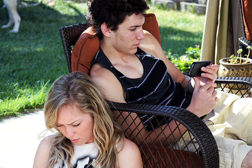 Teen couple relaxing on patio with smartphone