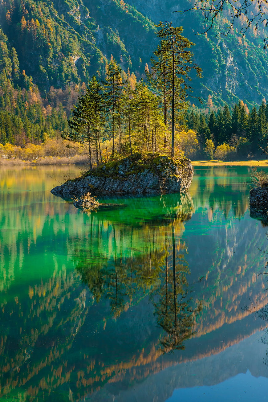 Serene Alpine Lake with Rocky Island and Forest Reflections