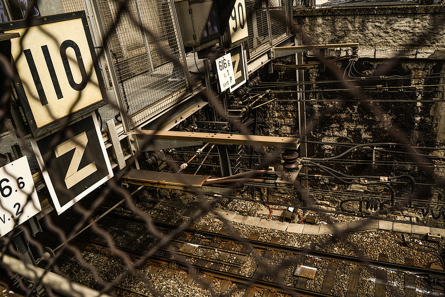Industrial railway tracks viewed through chain-link fence