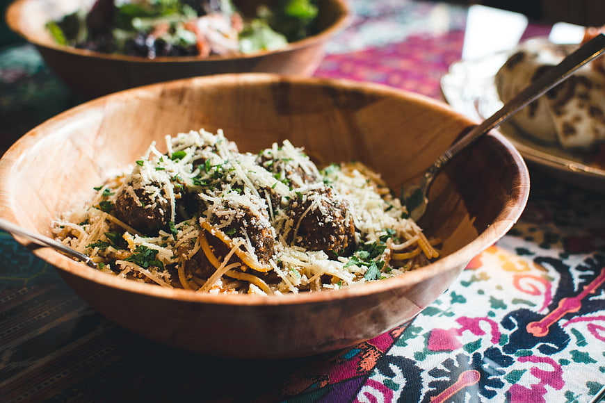 Rustic wooden bowl of spaghetti with meatballs and parmesan cheese