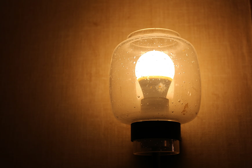 Illuminated light bulb inside glass jar with water droplets