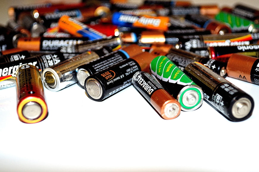Assorted AA and AAA Batteries Scattered on White Surface